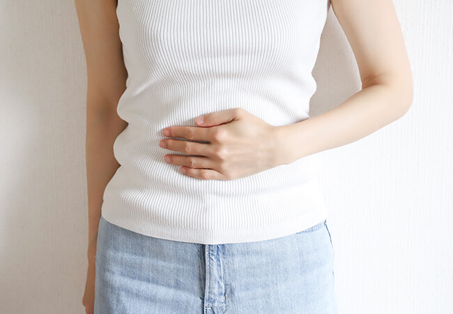 左手でお腹をおさえる女性