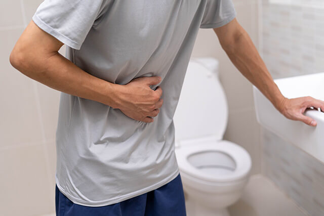 トイレで腹部に手を当てている男性