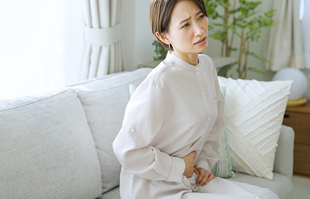 腹部に手を当て痛がっている女性